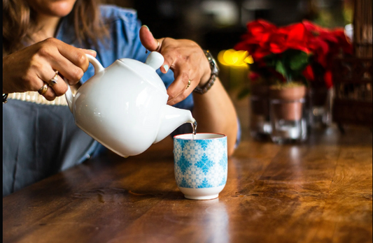 Tasse de tisane chaude sur une table, lumière douce en arrière-plan, illustrant un rituel du soir naturel pour favoriser le sommeil